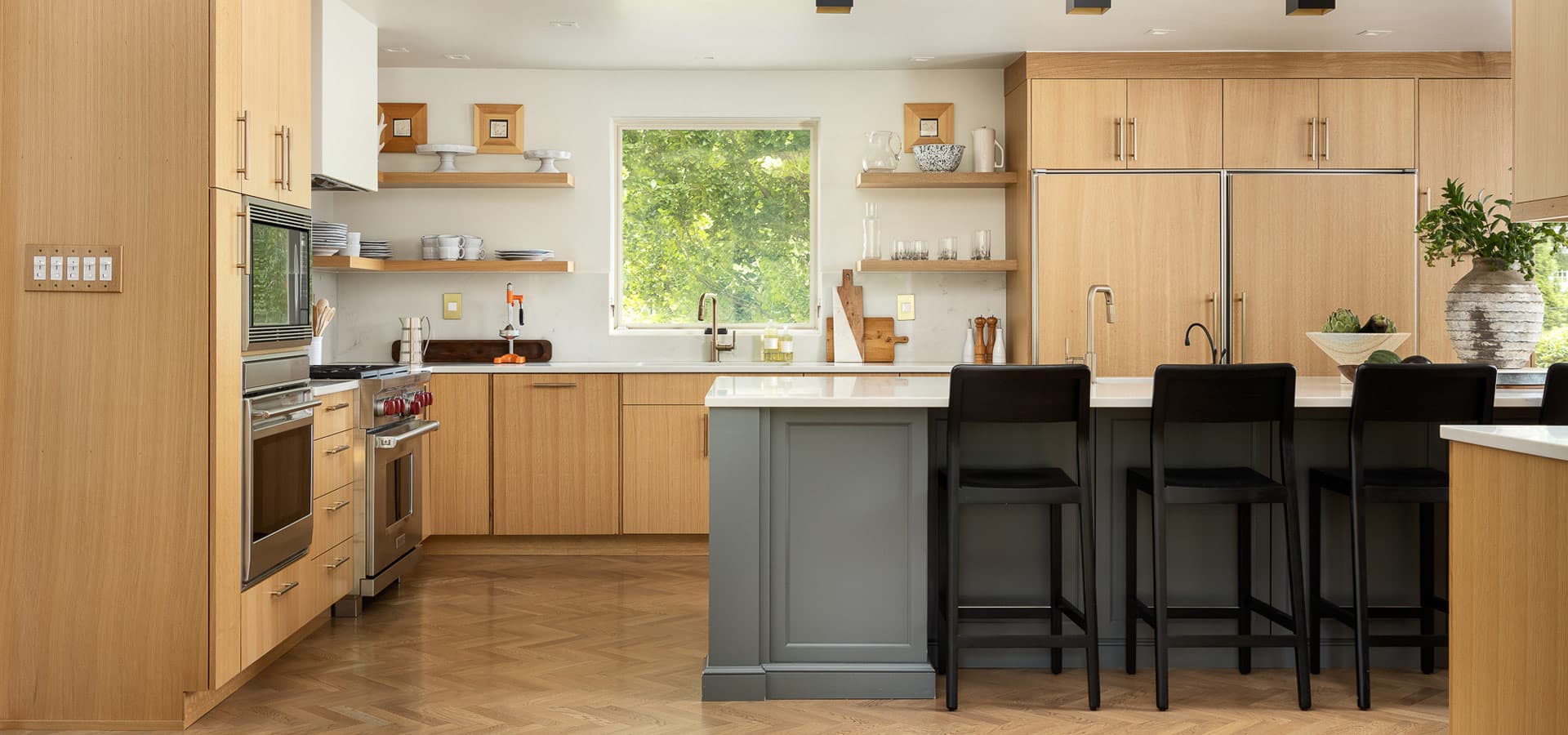 Pirela Atelier. Modern kitchen with light oak cabinets and professional stainless steel appliances.
